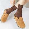 A pair of brown suede clog-style shoes paired with thick, ribbed brown tube socks.
