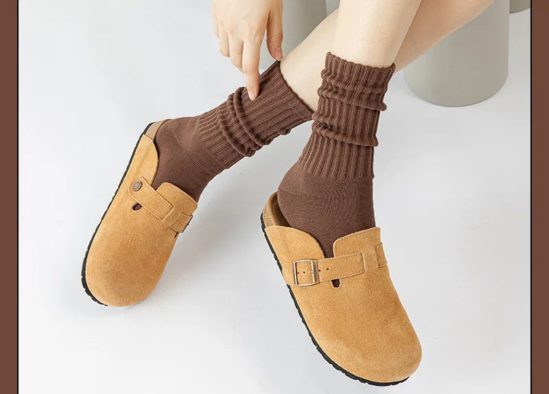 A pair of brown suede clog-style shoes paired with thick, ribbed brown tube socks.