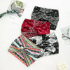 A collection of three patterned fabric headbands including a black and white print, a red paisley design, and a multicolored 