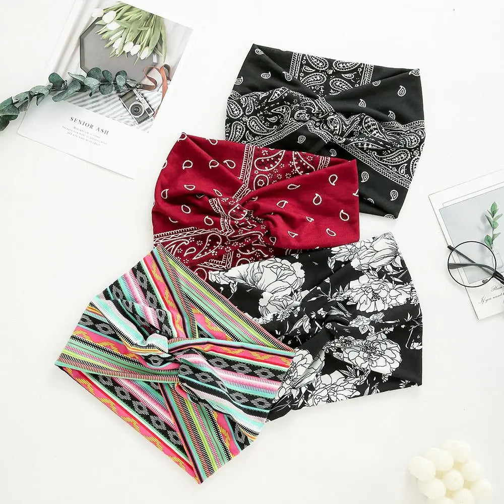 A collection of three patterned fabric headbands including a black and white print, a red paisley design, and a multicolored 