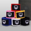 A stack of professional cotton boxing hand wraps in red, pink, yellow, blue, and black featuring a white stylized skull desig