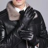 Un homme en veste en cuir noire et chemise blanche à col de fourrure, tenant des gants d'hiver en cuir noir.