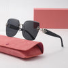 A pair of black frameless sunglasses resting on a pink leather wallet next to a pink box.