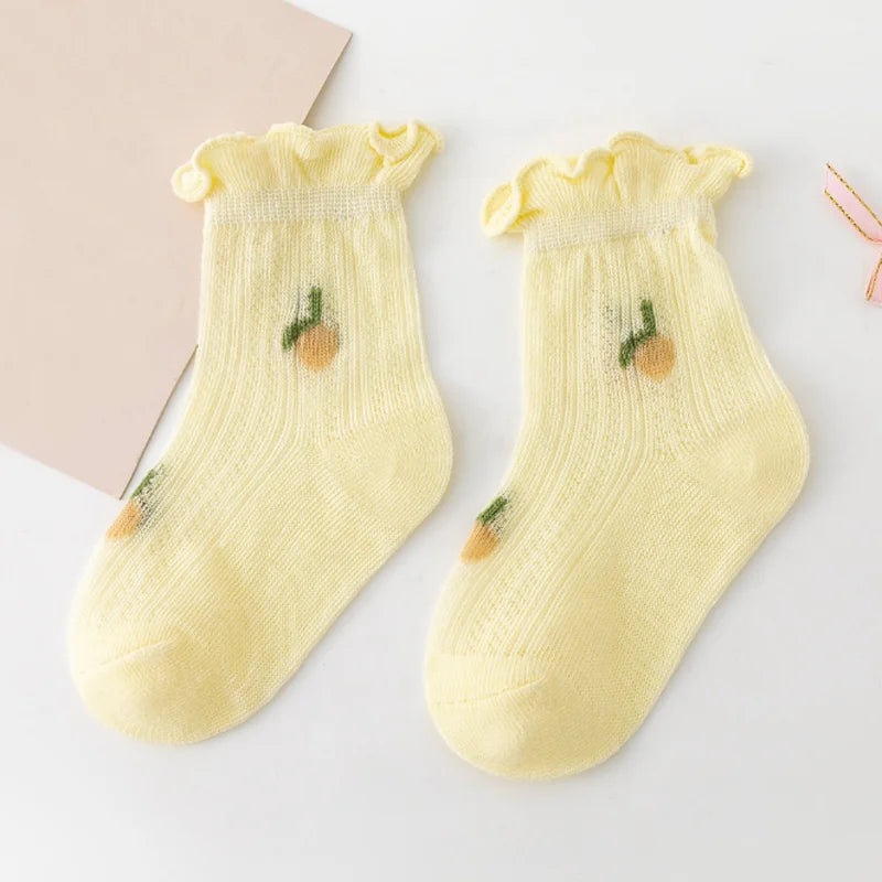 A pair of yellow knitted baby socks with small olive-green designs displayed on a white background.