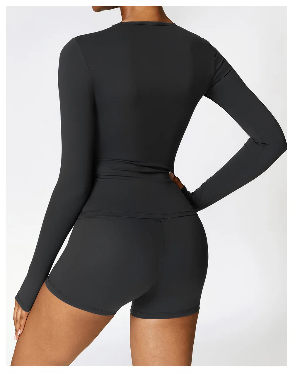 A woman wearing a long-sleeved, fitted black yoga and fitness t-shirt.