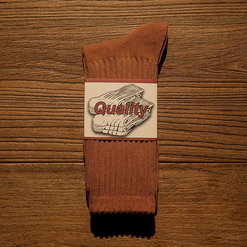 A brown tube sock with a white graphic featuring the word Quality