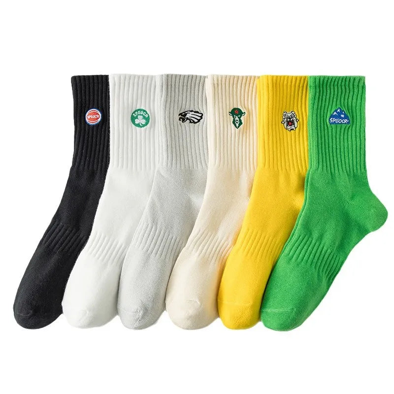 A set of five men's athletic embroidered crew socks in black, white, cream, yellow, and green.