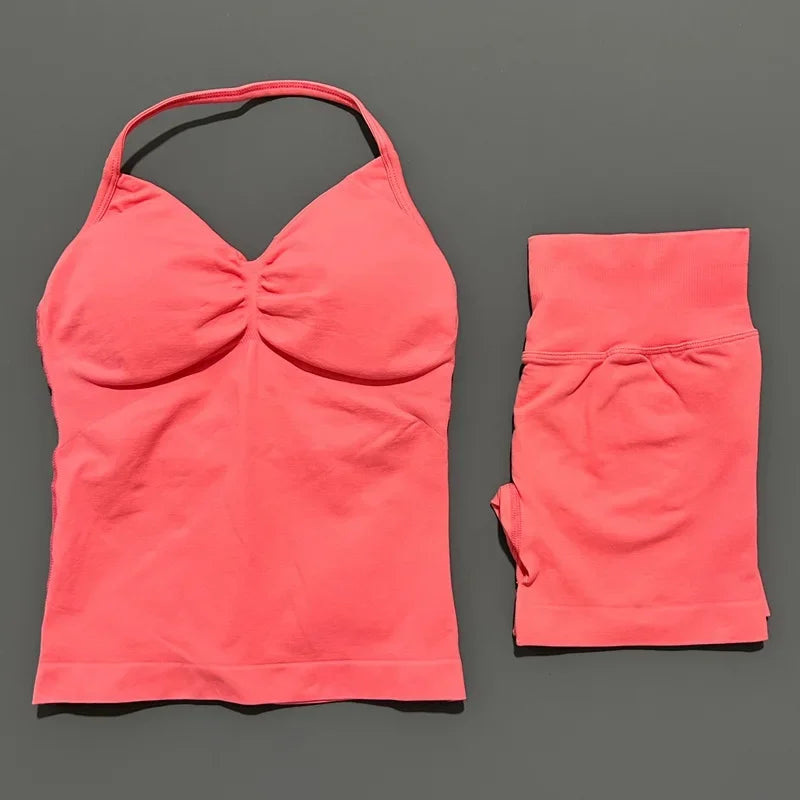 A bright coral pink seamless fitness set for women, consisting of a cropped top and matching shorts.