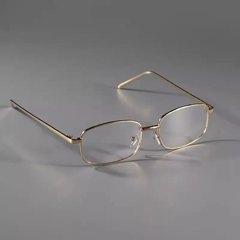 A pair of thin gold-rimmed eyeglasses with clear lenses resting on a gray surface.