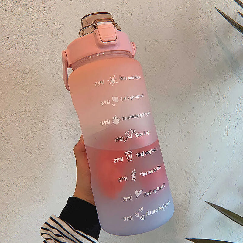 Botella de agua aislada rosa motivacional con tapa de pajita, sostenida contra un fondo blanco.