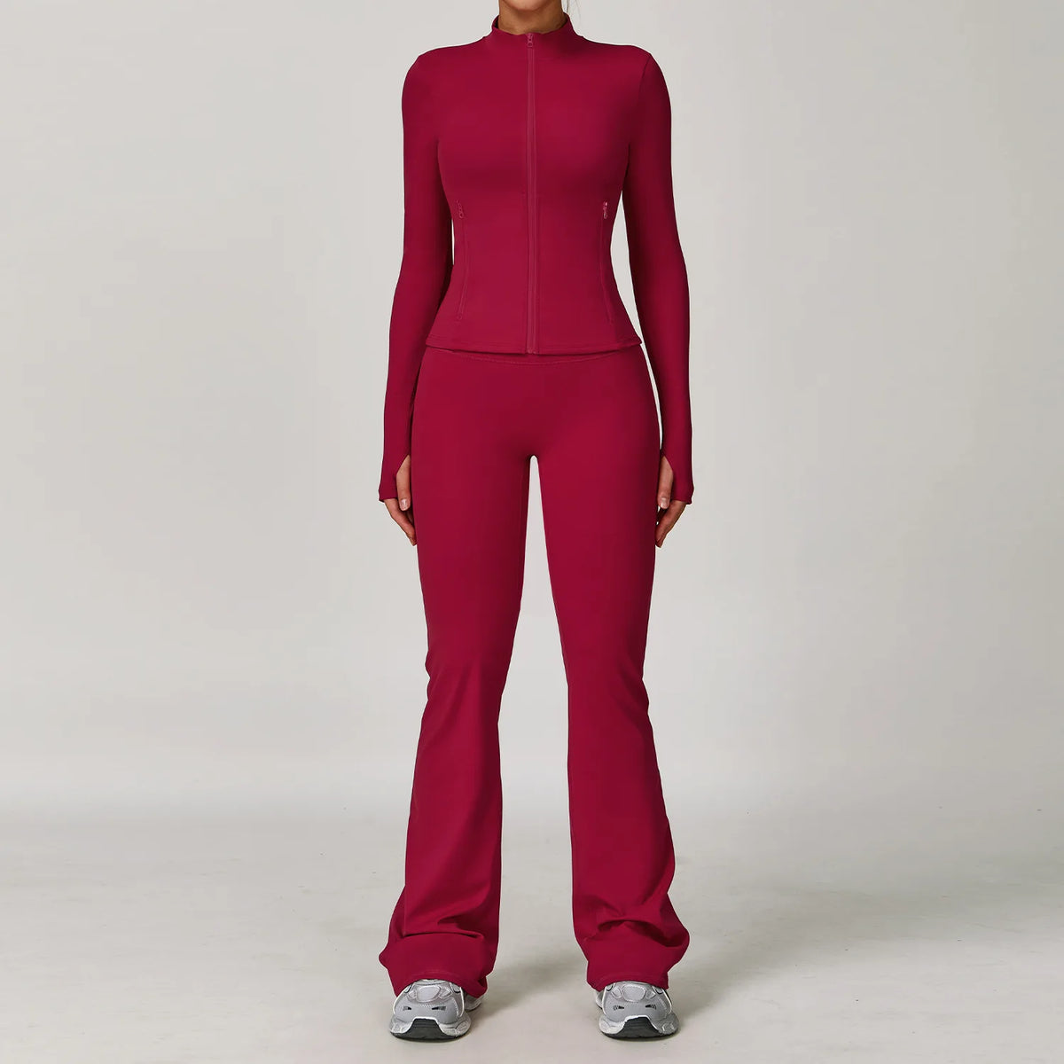 A woman wearing a long-sleeved maroon yoga sports set consisting of a top and pants.