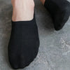 Black knitted boat socks shown on a foot against a gray background.