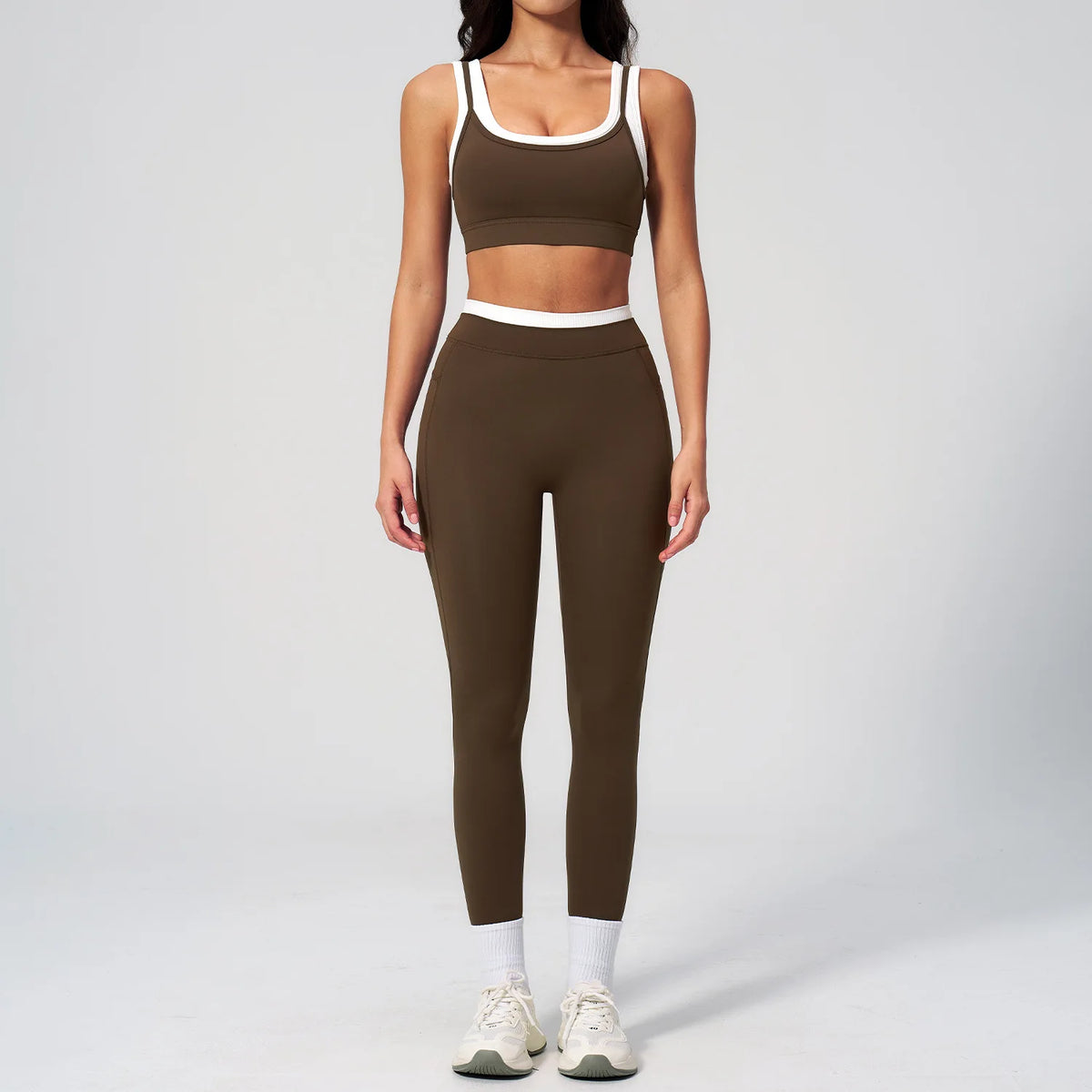 Eine Frau modelliert ein zweteiliges braunes Yoga- und Trainingsanzugset mit क्रॉपtop und passenden Leggings.