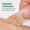 Une main applique du ruban médical beige sur la peau, démontrant une adhérence fiable.