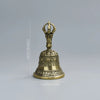 Clochette de bronze à tenir avec un dessus orné et une base évasée, présentée sur fond gris.