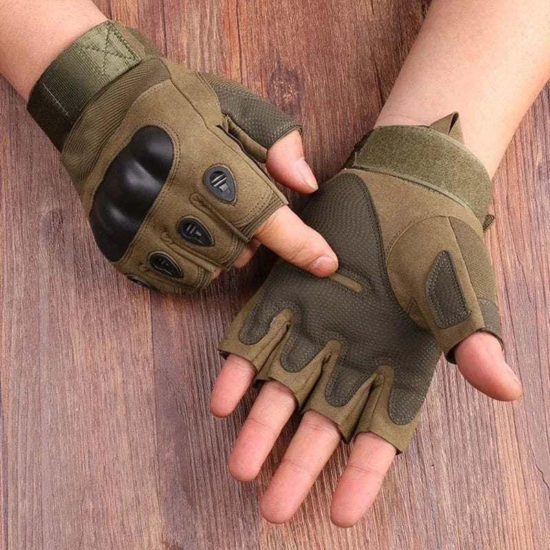 A pair of olive green half finger tactical gloves being held by a person against a wooden background.