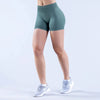 A person wearing teal seamless high-waisted yoga shorts and white athletic shoes.
