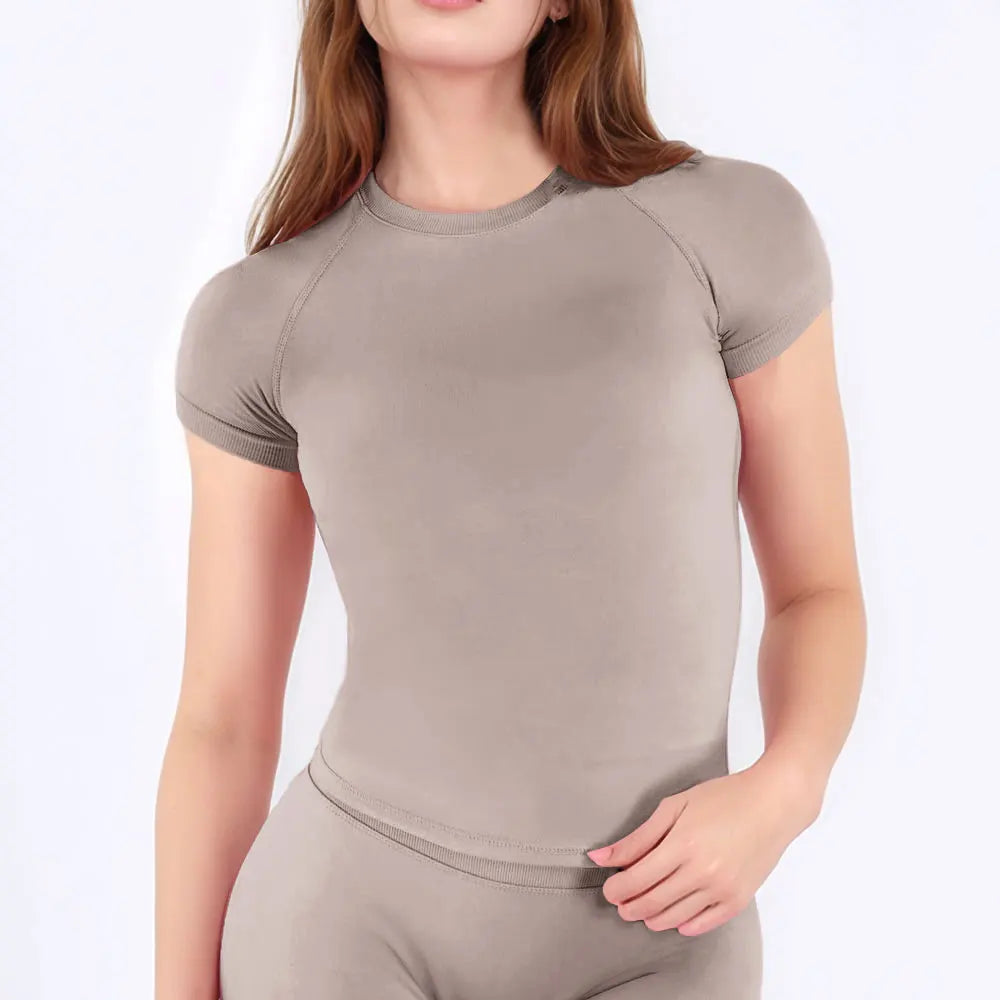 A woman wearing a fitted, short-sleeve performance fitness top in a taupe color.