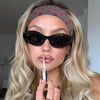 Eine Frau präsentiert ein schwarz-polka-dot-Stoff-Haarband und hält einen silbernen Vape-Pen.
