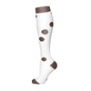 A pair of white compression socks with brown polka dots.