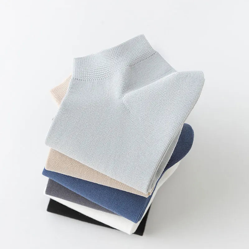 A stack of six pairs of men's combed cotton socks in various shades of gray and blue.