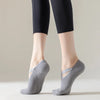 Un par de calcetines de yoga y pilates grises Comfort Fit puestos en los pies de una persona.