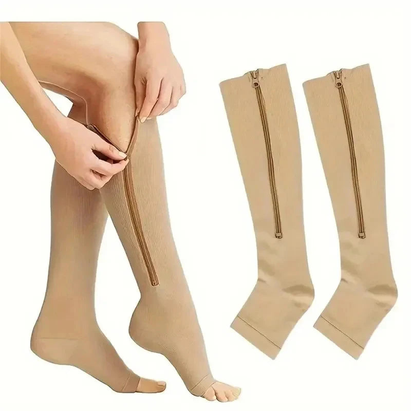 A pair of beige compression stockings with zippers are shown on a person's leg and laid out separately.