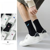 A close-up of men's athletic embroidered crew socks in black and white, shown being worn on a foot.