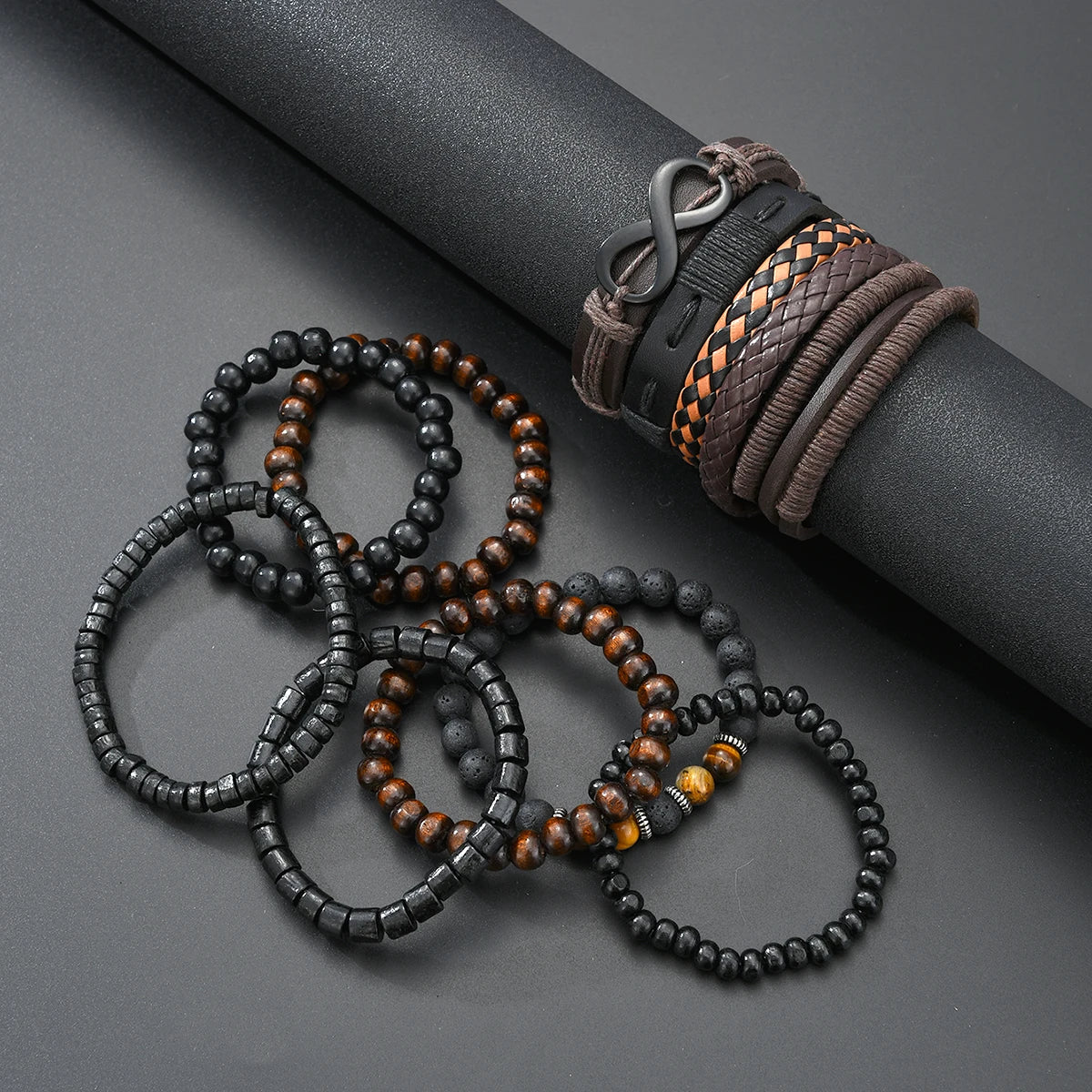 A collection of dark and amber beaded leather bracelets and a woven leather wristband resting on a dark surface.