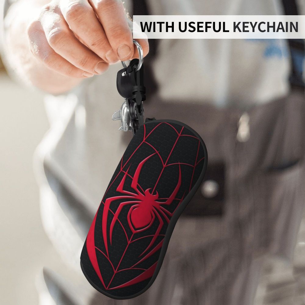 A black spider web shaped pouch attached to a keychain, being held by a person.