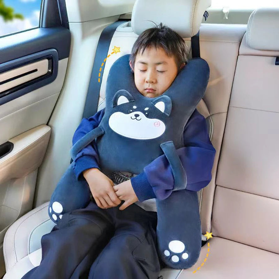 Un jeune garçon repose sa tête sur un oreiller ergonomique en forme d'ours bleu et blanc dans un siège de voiture.