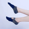 A close-up of a person's foot wearing dark blue and gray breathable silicone yoga and fitness socks.