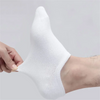 White ankle socks being held by a hand, showing the texture and fit of the boat style sock.