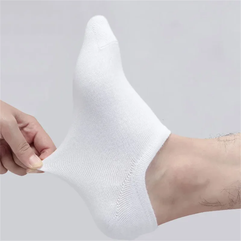 White ankle socks being held by a hand, showing the texture and fit of the boat style sock.