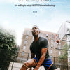 A man wearing a black shirt and blue shorts is performing an exercise with an orange basketball outdoors.