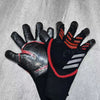 A pair of black and red goalkeeper football gloves lying on a gray surface.