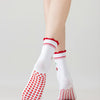Chaussettes de yoga blanches avec broderie rouge et adhérence antidérapante sur le pied d'une personne.