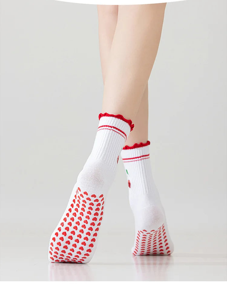 Chaussettes de yoga blanches avec broderie rouge et adhérence antidérapante sur le pied d'une personne.