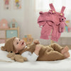 Neugeborenes Baby liegt auf einer weißen Oberfläche neben einem rosa handgewebten Teddytier Fotoprodukt.