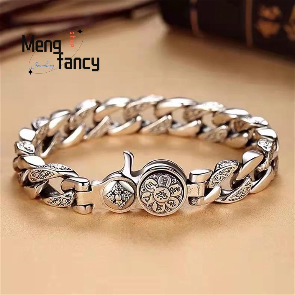 A silver mantra charm bracelet with interlocking links and a round charm on a light brown surface.