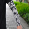 Close-up of a person's arm wearing black and white floral tattoo sleeves for sun protection.