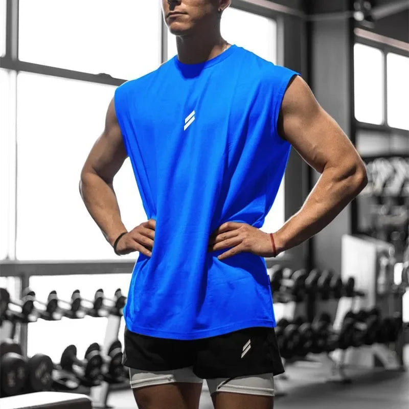A male model wearing a bright blue quick-drying sleeveless fitness tank top in a gym setting.
