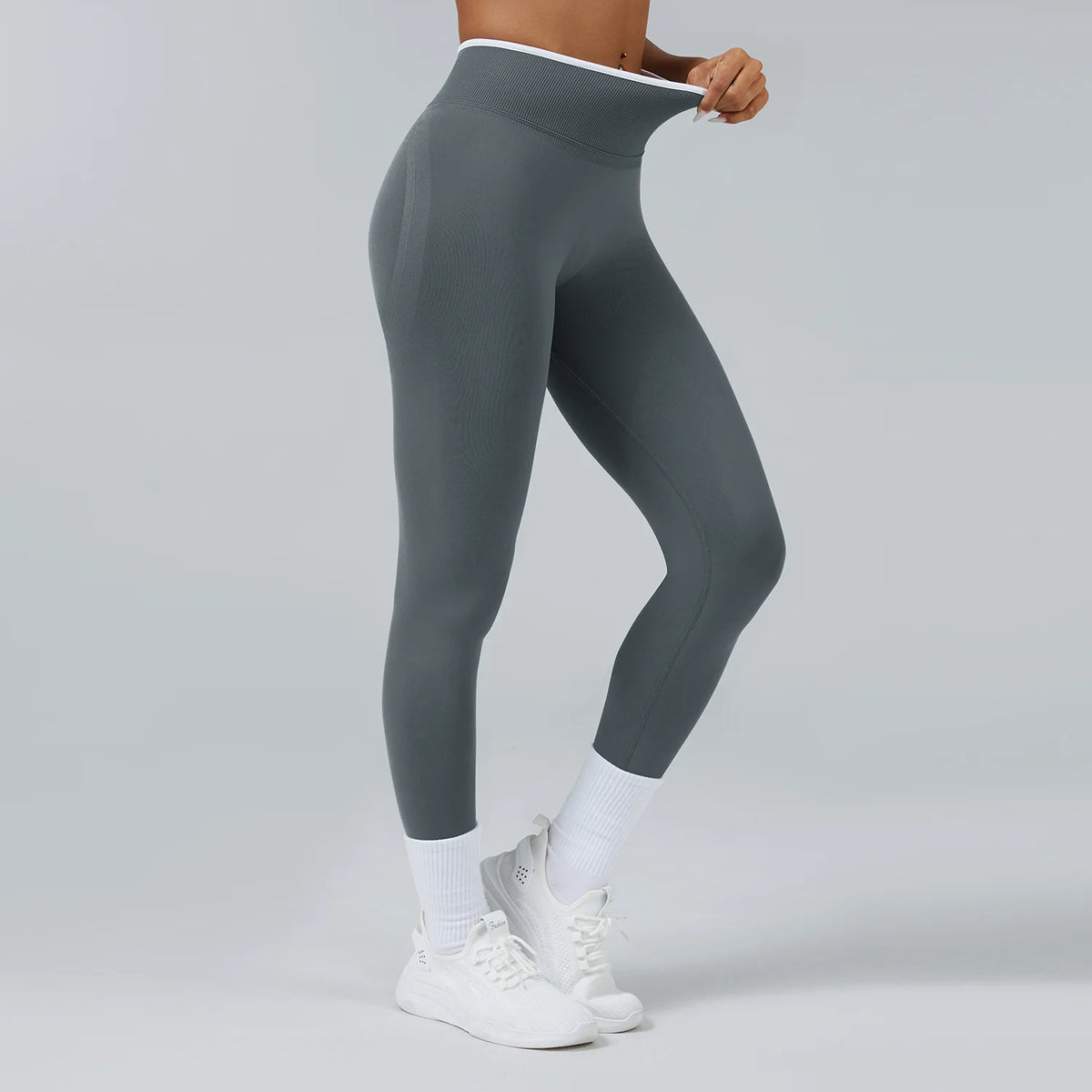 A person wearing gray high-waist yoga leggings and white socks, standing against a light background.