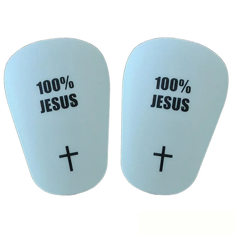 A pair of light blue soccer shin guards featuring the text 100% JESUS and a cross symbol.