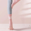 Pink ribbed yoga socks with white stripes worn on a person's foot and ankle.