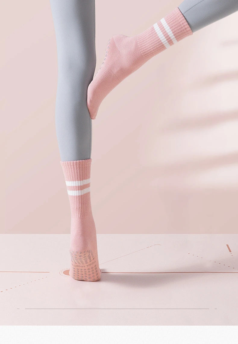 Pink ribbed yoga socks with white stripes worn on a person's foot and ankle.