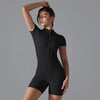 A model wearing a black seamless yoga jumpsuit, posing against a gray background.