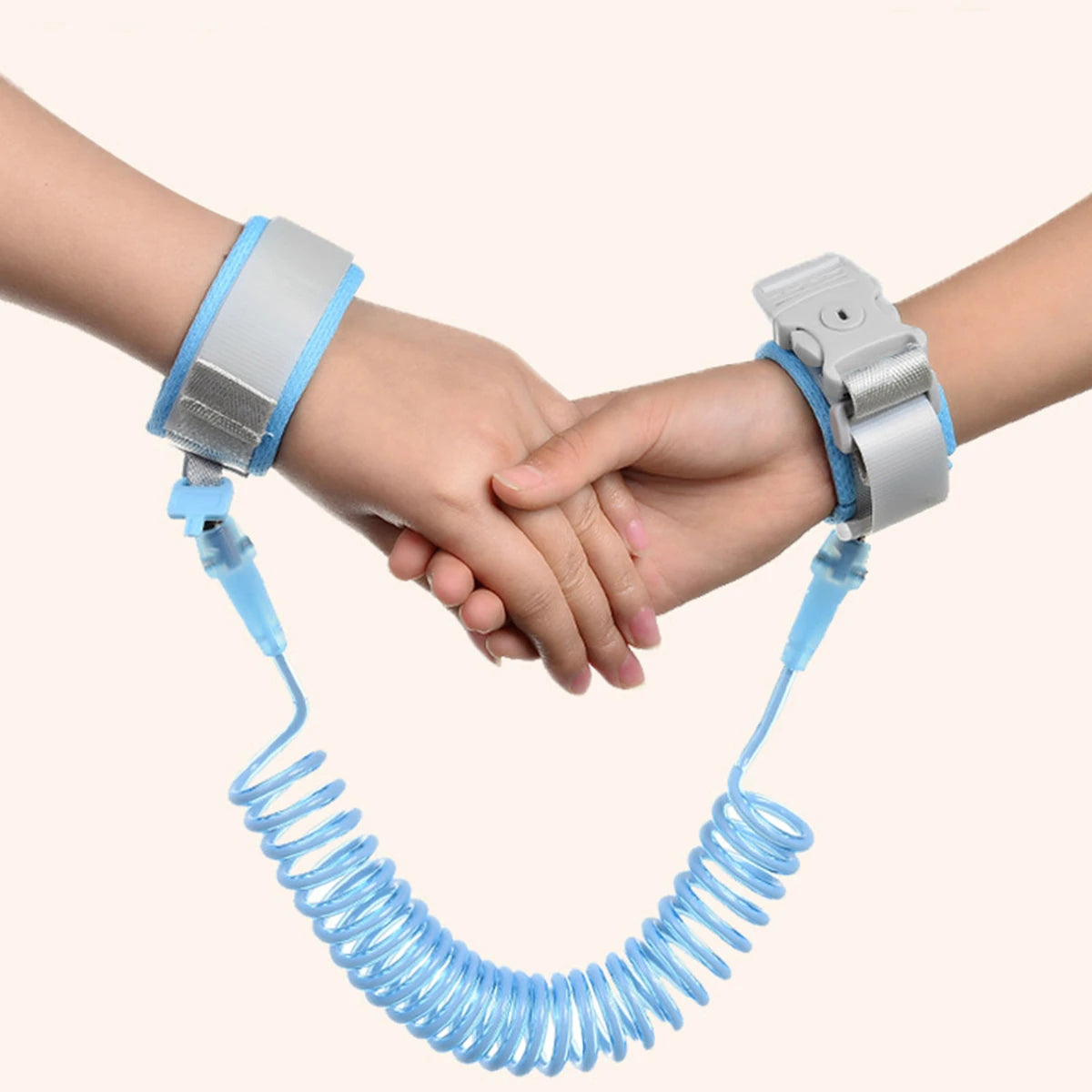 A hand wearing a silver wrist harness is connected by a blue cord to another hand, demonstrating an adjustable child safety h