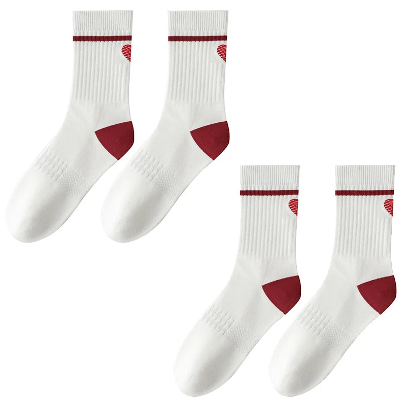 A set of white crew socks with maroon stripes and heel accents for athletic activities