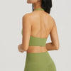 A model wearing a olive green halter neck sports bra top and matching leggings, shown from the back.